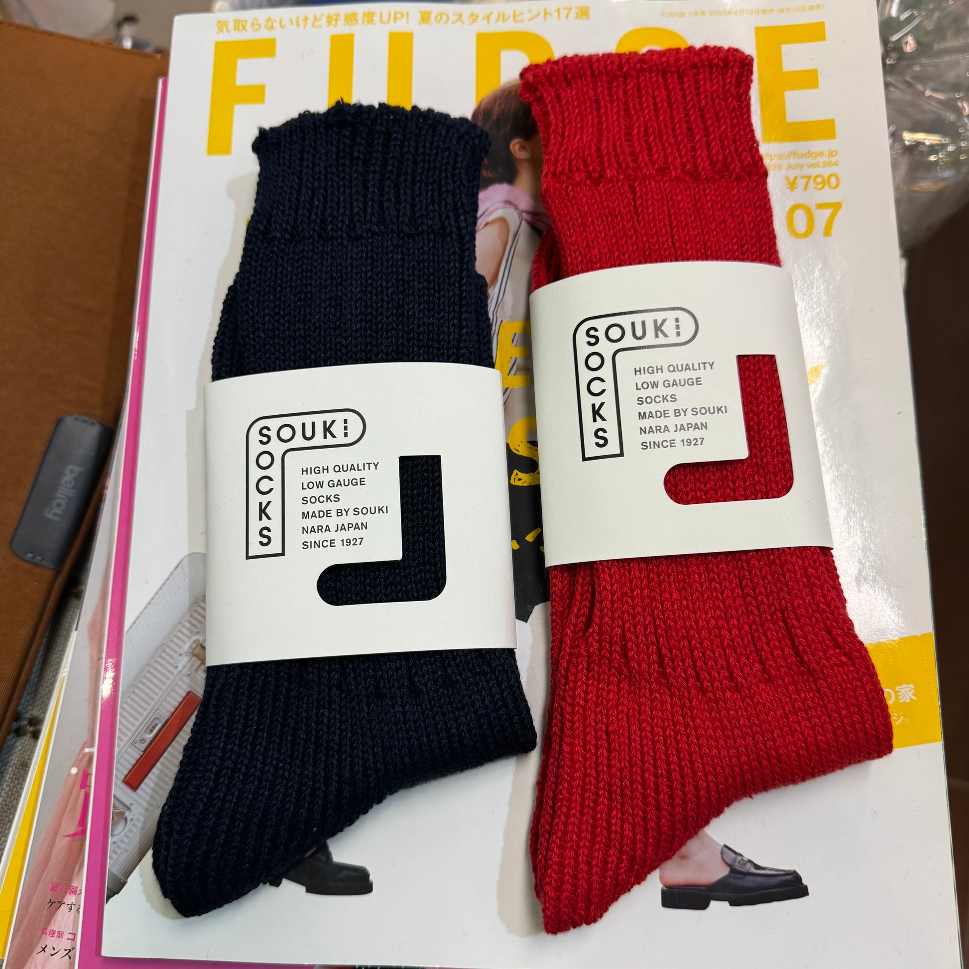 Two pairs of socks, one black and one red, with 'SOUKI' branding on a magazine cover.