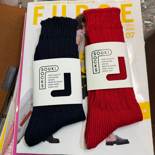 Two pairs of socks, one black and one red, with 'SOUKI' branding on a magazine cover.